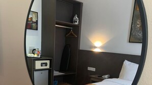 A hotel room with a bed, a wardrobe, a desk with a telephone, and a mirror reflecting the room. - Sentral View Hotel (Bintulu)