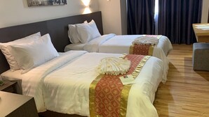 A hotel room with two beds, a wooden floor, and a desk with a chair. - Sentral View Hotel (Bintulu)