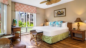 A bedroom with a large bed, a view of greenery outside, wicker furniture, and a ceiling fan. - 🏖️Keauhou Ocean-View Condo with Shaded Lanai & 2 King Beds | Kanaloa 1501 (Kailua Kona)