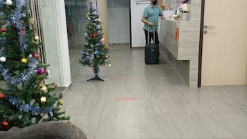 A hotel lobby with a reception desk, a Christmas tree, and a seating area.
