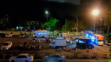 A parking lot with several vehicles and people.