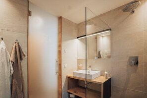 Une salle de bain moderne avec une douche à parois de verre, un meuble-lavabo en bois et un grand miroir.