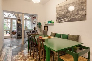 A dining area with a green table, chairs, and a view of a cityscape through a window.
