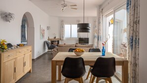 A dining area with a table, chairs, a bowl of fruit, a television, and a sofa in the background. - Apartment 'Casa Sydhavshytten' with Sea View, Wi-Fi and Air Conditioning (Nerja)
