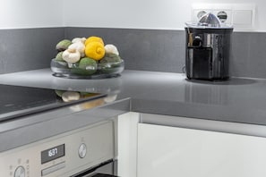 Een keuken met een glazen schaal vol groenten, een zwart apparaat en een digitale klok.