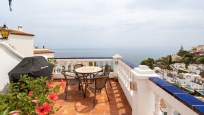 A terrace with a table and chairs, a grill, and a view of the sea. - Apartment 'Casa Sydhavshytten' with Sea View, Wi-Fi and Air Conditioning (Nerja)