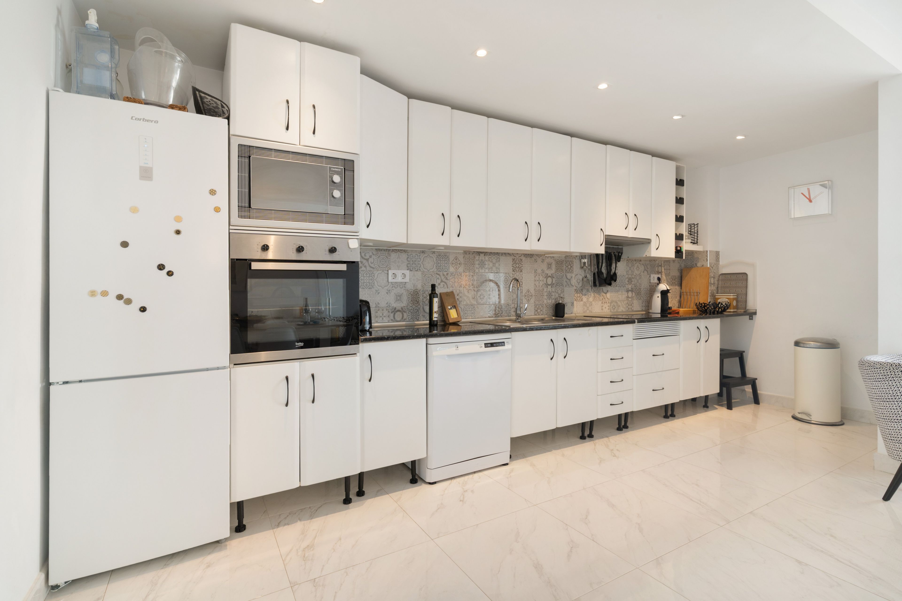 A modern kitchen with white cabinetry, a built-in oven, and a dishwasher.