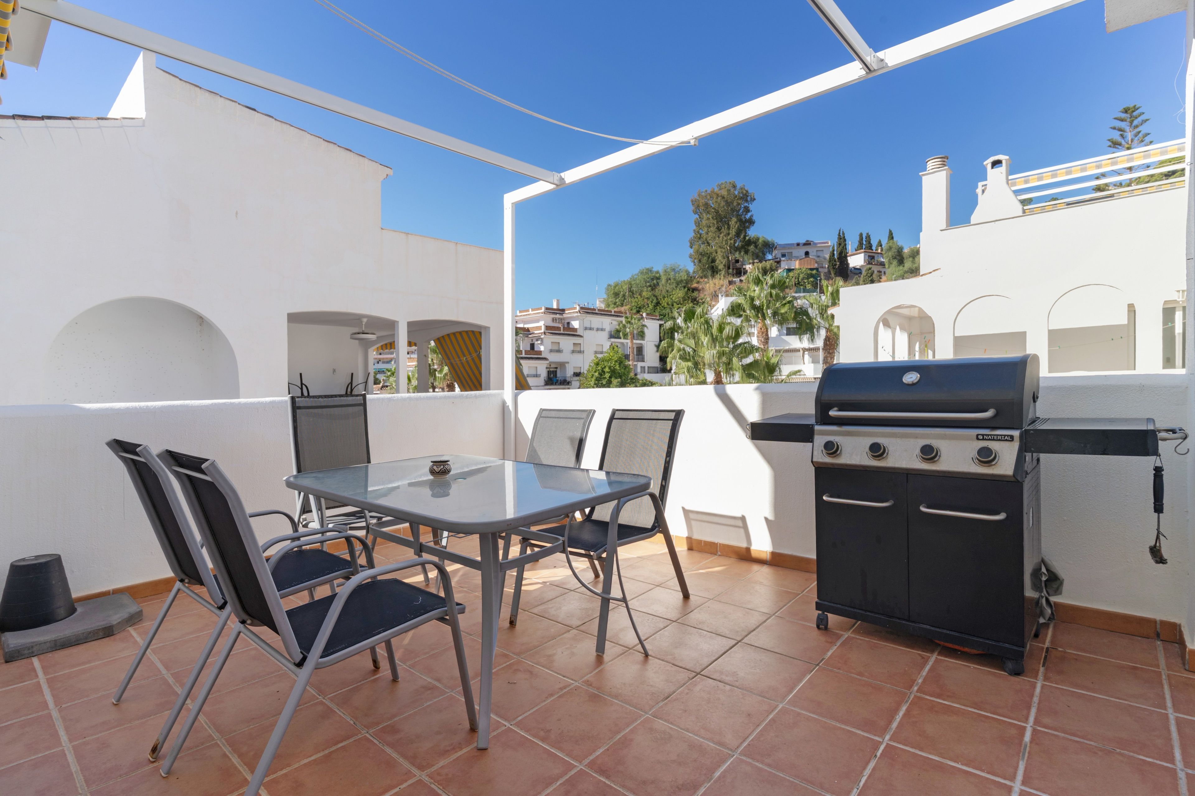 Un patio exterior con una parrilla, una mesa y sillas.