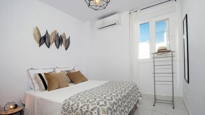 A bedroom with a bed, decorative wall art, a ladder, and an air conditioning unit. - Holiday Apartment "Casa Chana" with Terrace, Shared Pool and Jacuzzi (Almunecar)