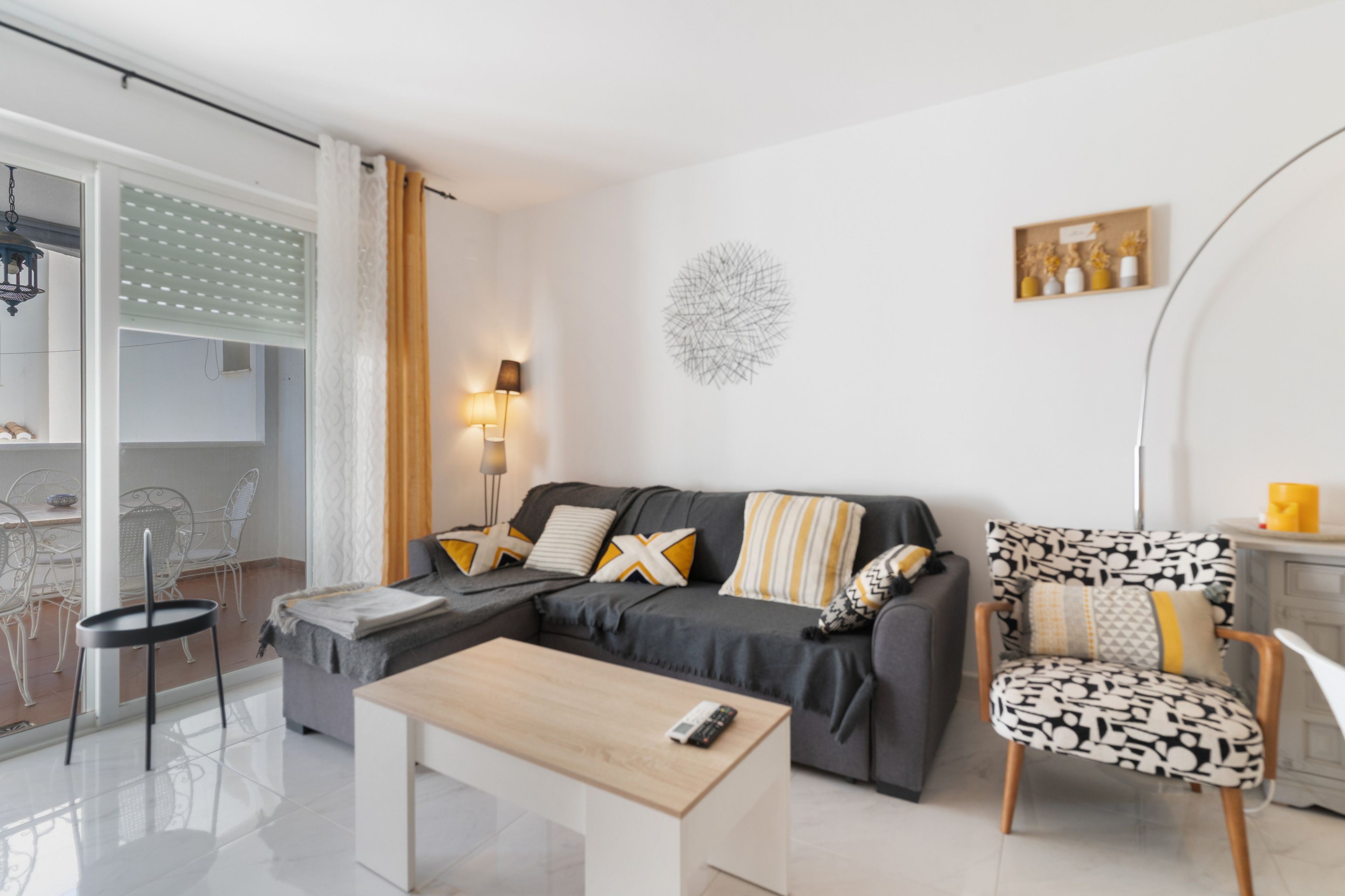 A modern living room with a sofa, a coffee table, a chair, and a dining area with chairs and a table.