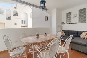 A terrace with a round table and white chairs, a grey sofa, and a decorative wall with framed items. - Holiday Apartment "Casa Chana" with Terrace, Shared Pool and Jacuzzi (Almunecar)