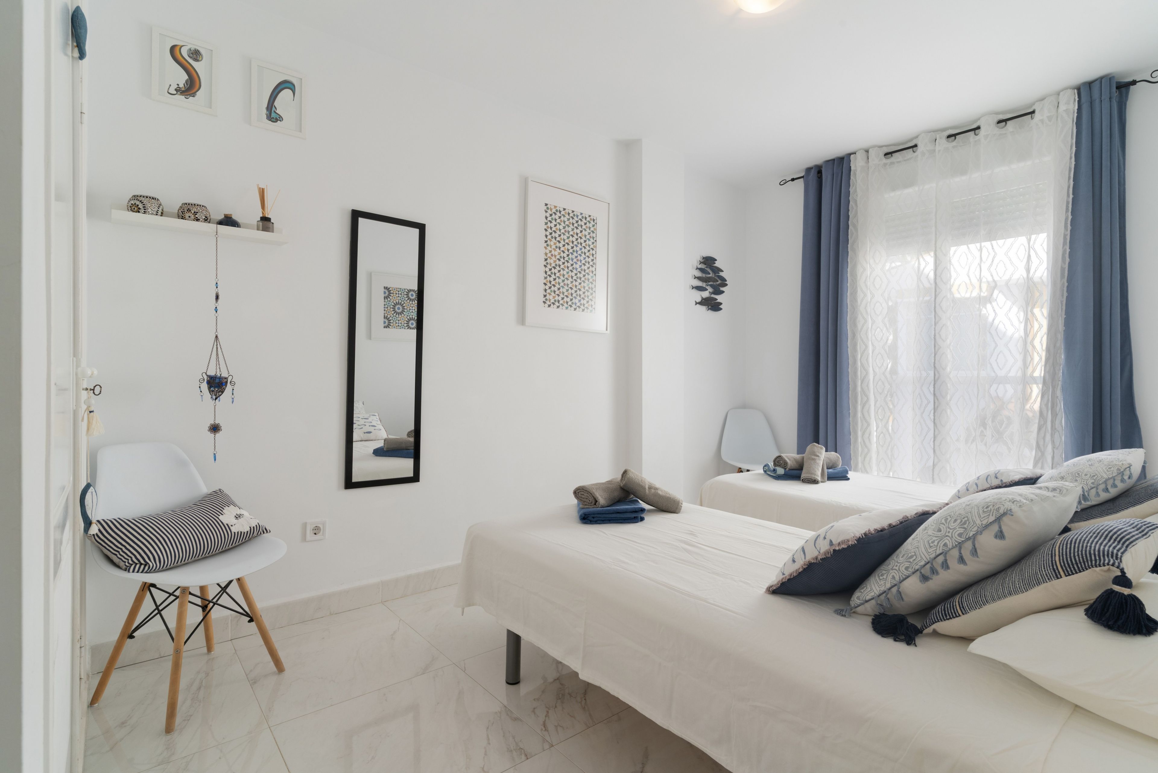 Une chambre à coucher comprenant un lit, une table de chevet, une chaise et un mur orné de tableaux encadrés.