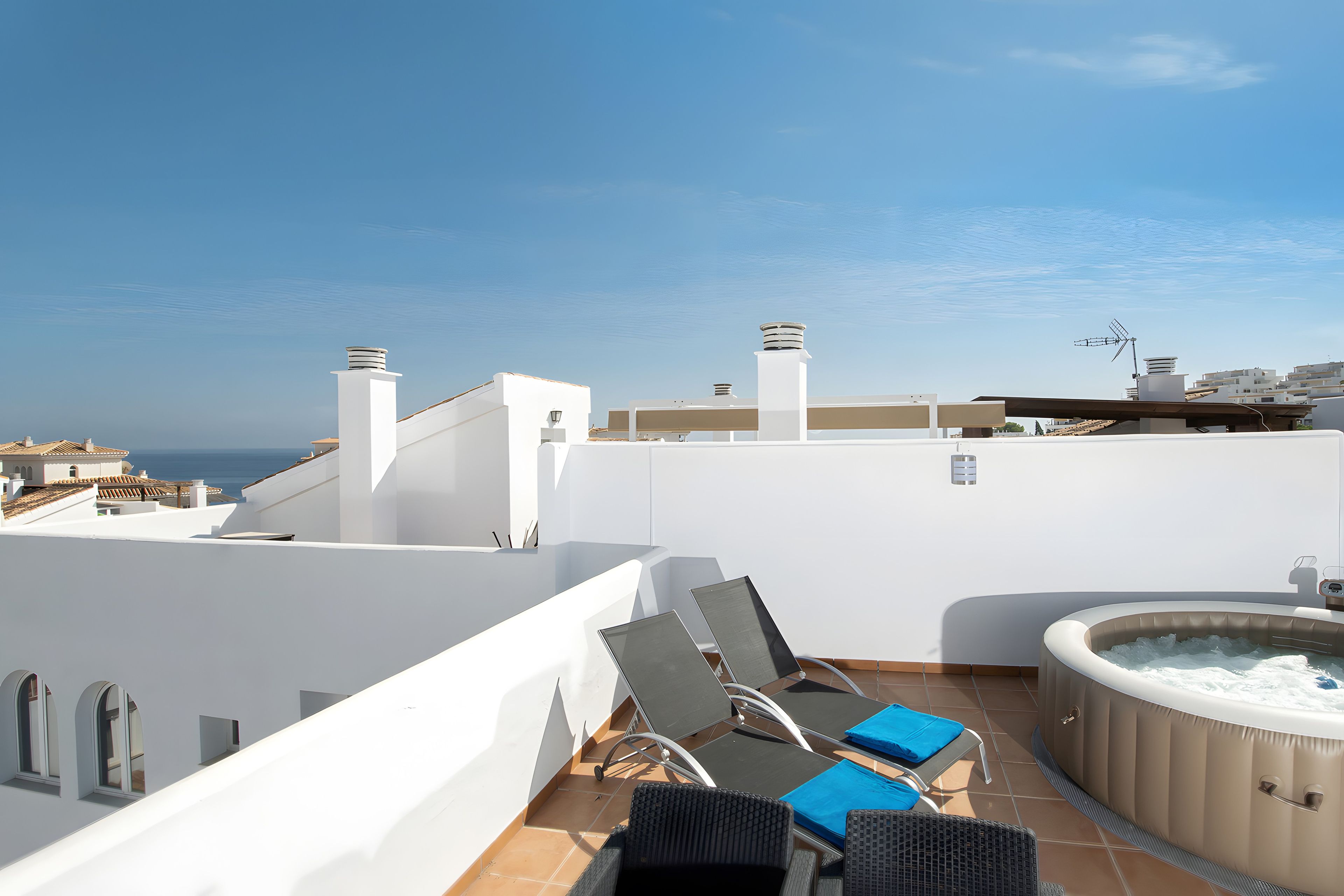 Eine Dachterrasse mit Liegestühlen, einem Whirlpool und Blick auf das Meer.