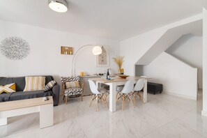 A modern living space with a dining area, a sofa, and a staircase. - Holiday Apartment "Casa Chana" with Terrace, Shared Pool and Jacuzzi (Almunecar)