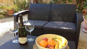 A wicker outdoor seating area with a bottle of wine, glasses, and a bowl of fruit. - Holiday Home 'Vista Marina' with Mountain Views, Garden and Wi-Fi (La Herradura)