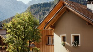 A mountain-view hotel with wooden architecture, a sloped roof, and a view of the surrounding mountains.