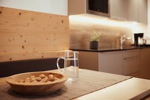 A kitchen with a wooden countertop, a clear glass pitcher, and a bowl of nuts.