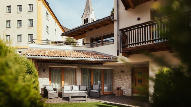 A courtyard with outdoor seating, a stone wall, and a view of a church steeple.