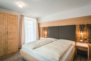 Ein Schlafzimmer mit einem hölzernen Kopfende, einem Bett mit weißer Bettwäsche, einem Nachttisch und einem Kleiderschrank.