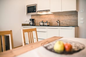 Eine moderne Küche mit Mikrowelle, Kaffeemaschine und Töpfen auf der Arbeitsfläche.