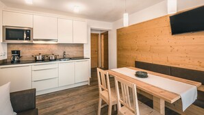 Een moderne keuken met witte kasten, een magnetron en een koffiezetapparaat.