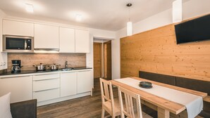 A modern kitchen with white cabinets, a microwave, and a wooden dining table with chairs.
