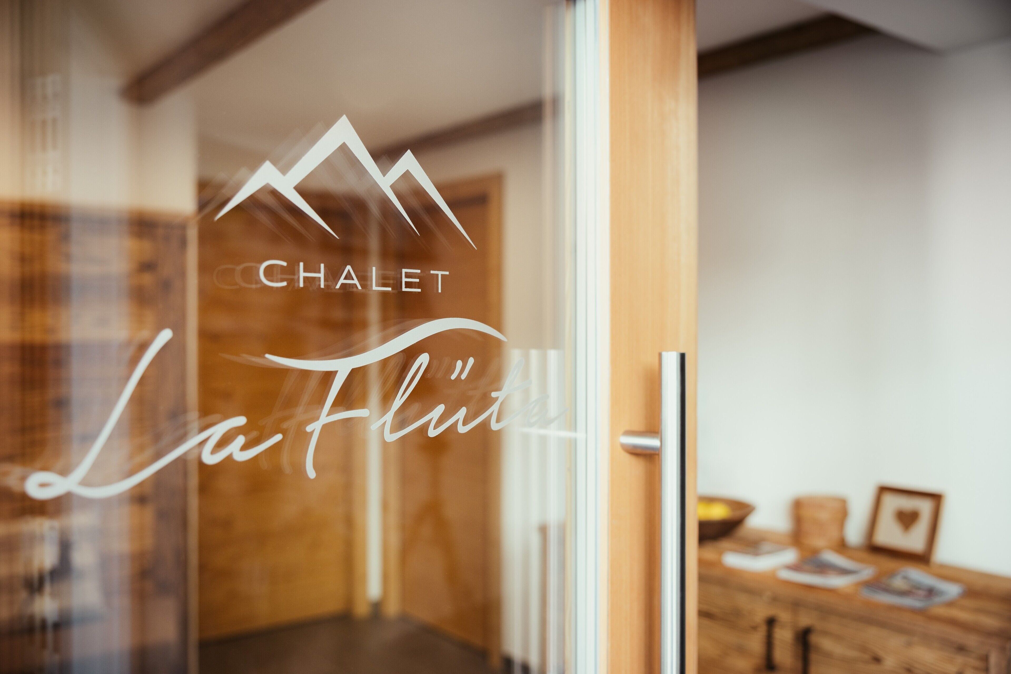 A glass door with the logo 'CHALET La Flute' and a blurred interior view.