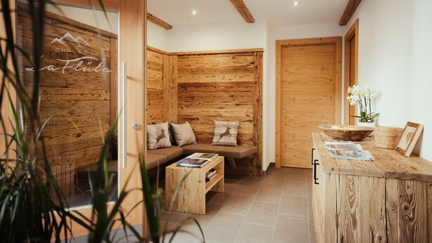 A wooden interior with a sofa, a wooden table, and a wooden wall.