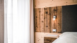A wooden-paneled room with a bed, a desk, and a wall socket.