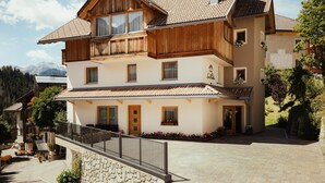 A two-story building with a balcony, a stone wall, and a paved courtyard.