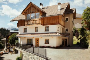 Un bâtiment à deux étages doté d’un balcon, d’un mur en pierre et d’une cour pavée.