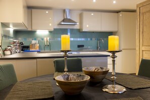 Kitchen features a central island with stove and range hood, white cabinets, and a blue and white tile backsplash.