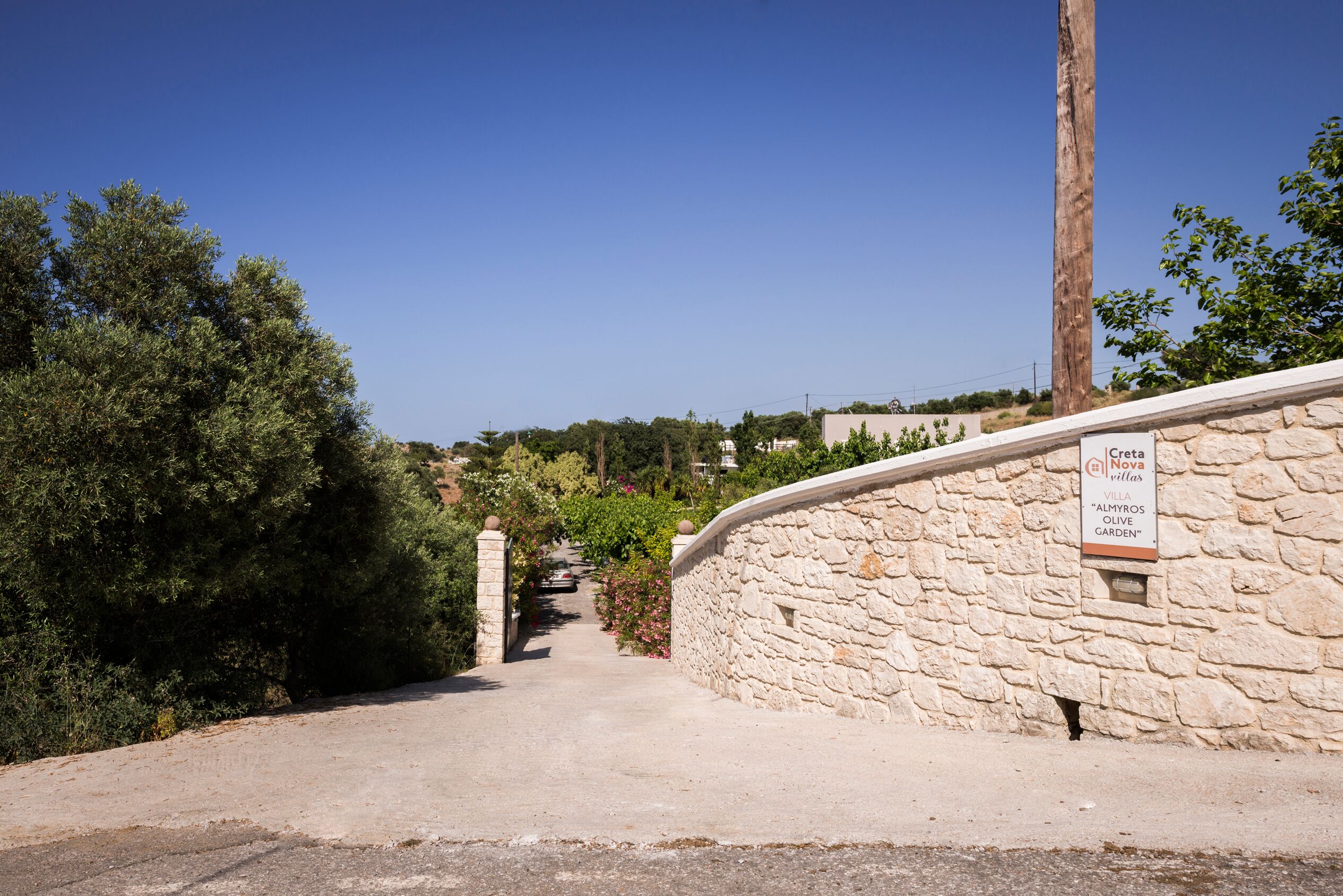 Eine Steinsäule mit dem Schild 'Creta Nova Villas' und 'Almyros Olive Garden'.