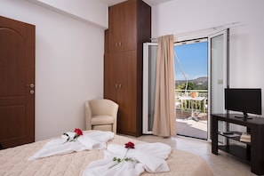 A hotel room with a bed, a chair, a TV, and a balcony with a view.