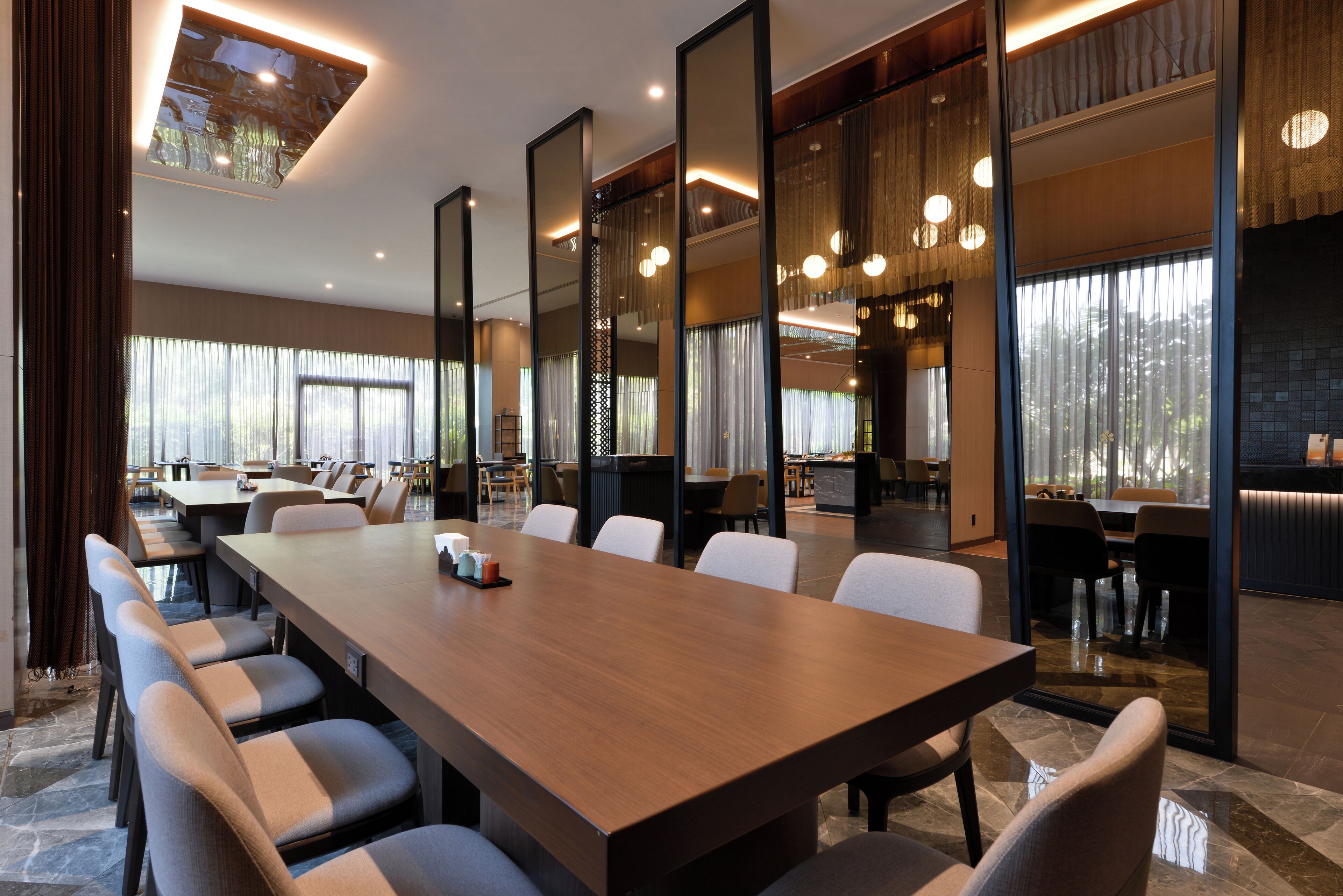 Uma sala de conferências moderna com uma mesa comprida, várias cadeiras e janelas amplas.