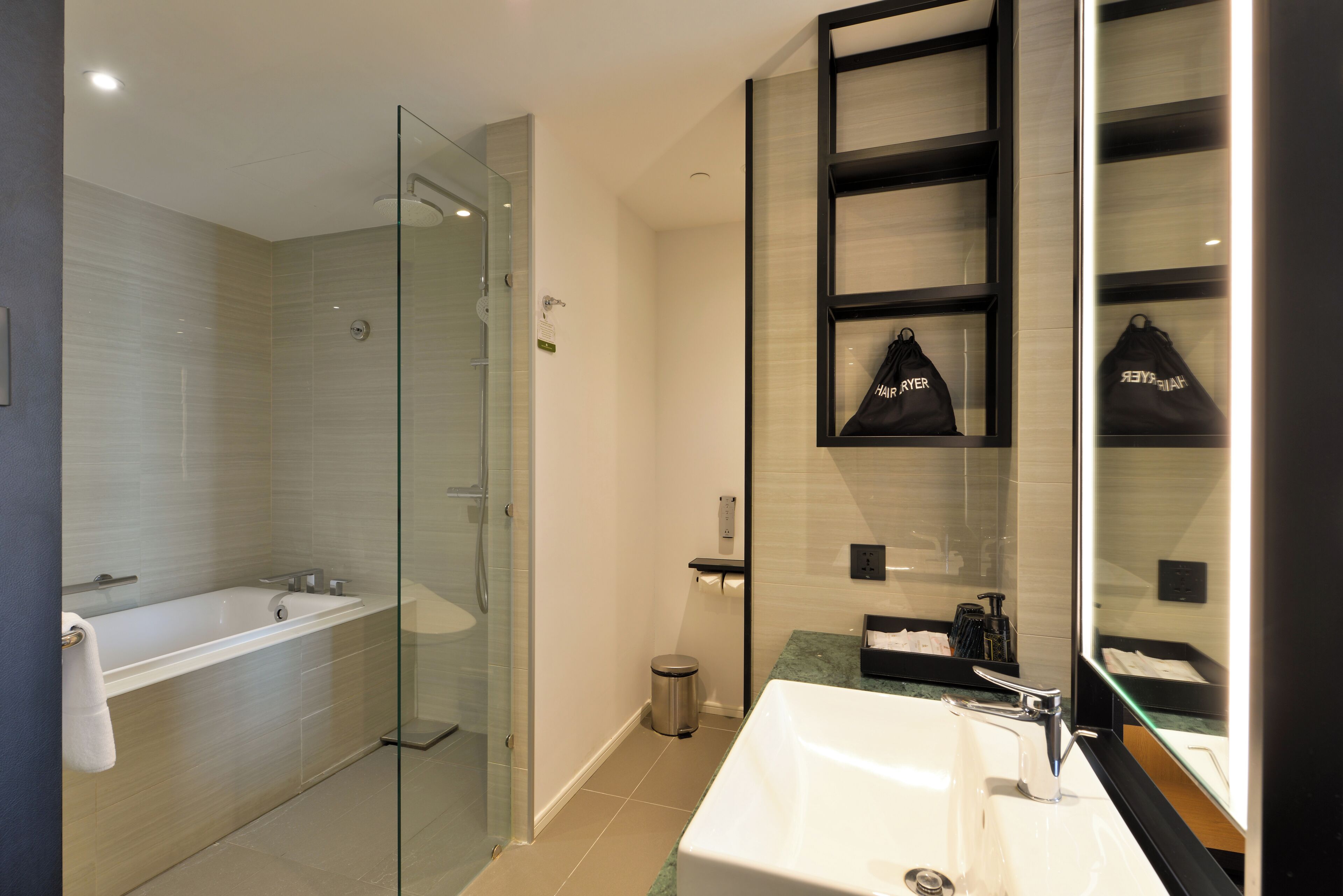 Un baño moderno con ducha envuelta en vidrio, una bañera independiente y un tocador con espejo.