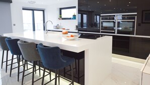 Une cuisine moderne avec un îlot central, des tabourets de bar et une grande fenêtre.