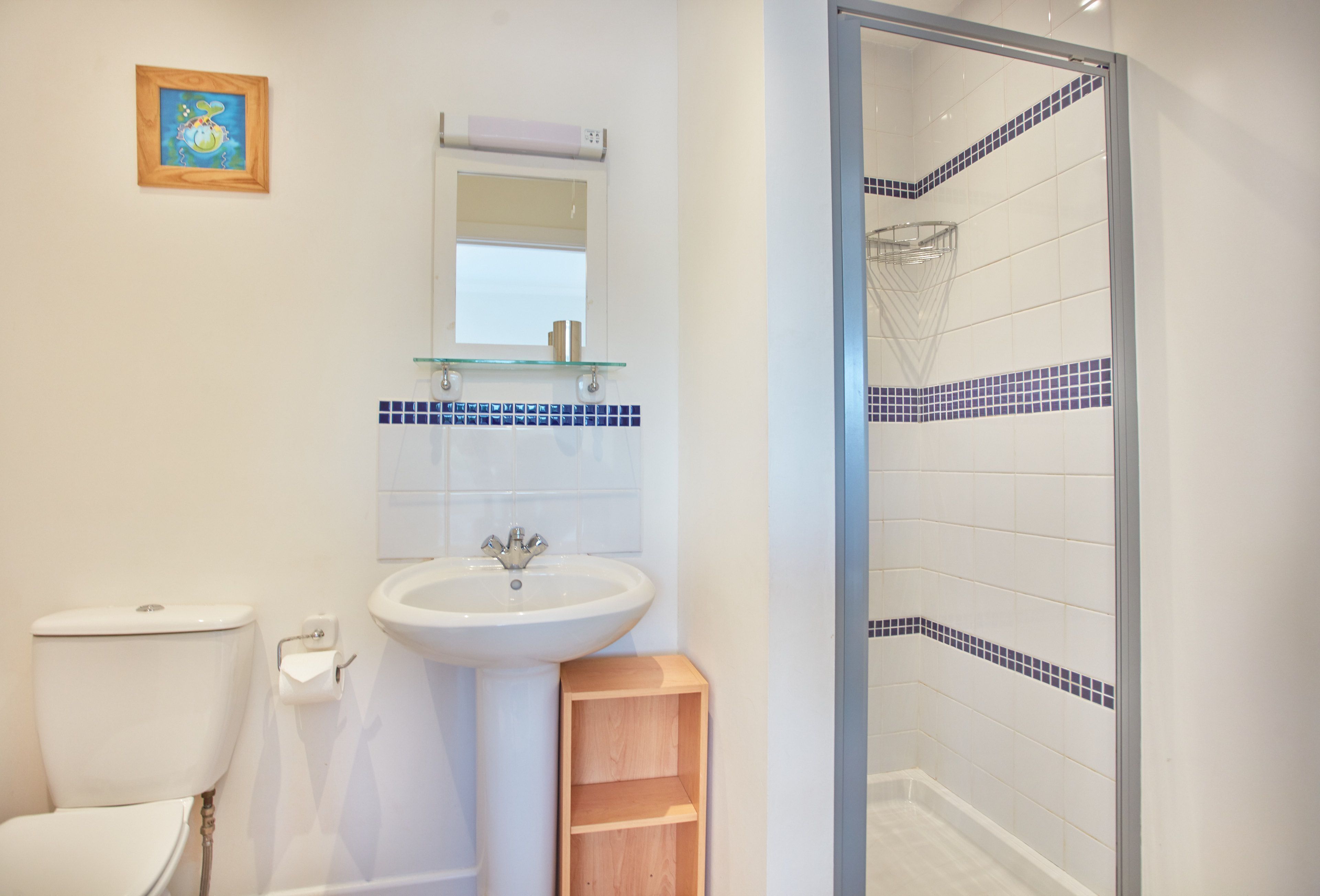 A bathroom with a toilet, sink, and glass shower enclosure.
