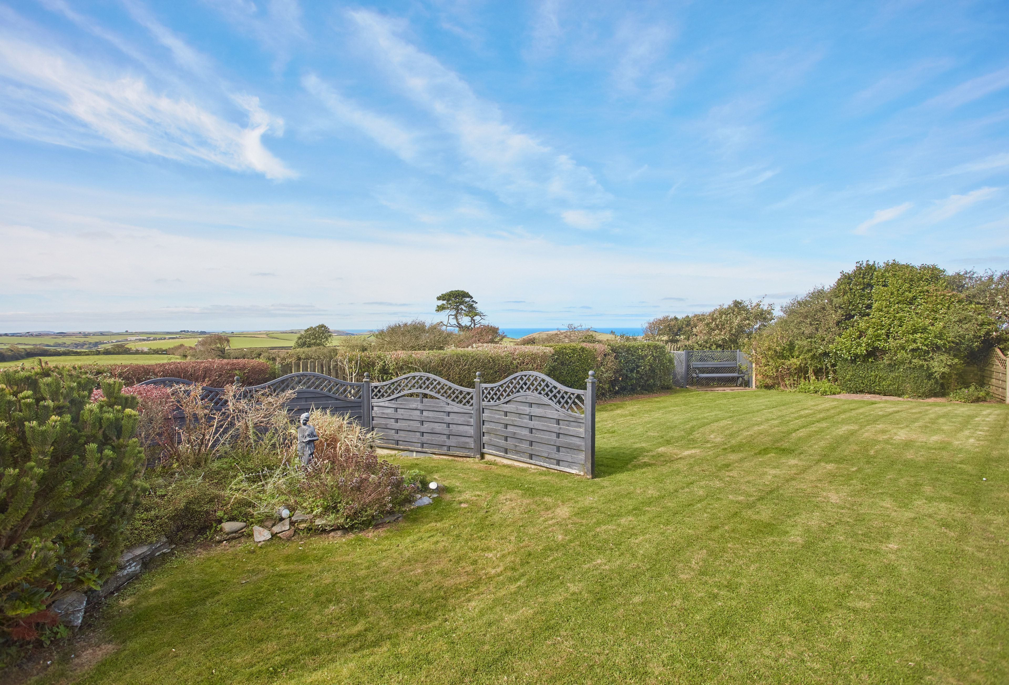 A well-maintained lawn with a decorative fence and a clear view of the surrounding countryside.