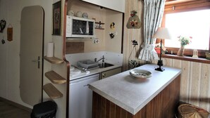 Una kitchenette compacta con microondas, pileta y una mesada pequeña.