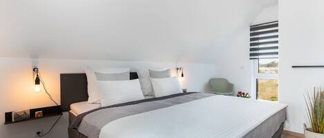 Un dormitorio moderno con una cama grande, mesitas de noche y una ventana con persianas.