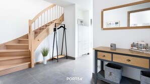 En modern inredning med en trätrappa, en vit vägg, en spegel och ett konsolbord med förvaringslådor.