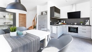 Ett modernt kök med vita skåp, en inbyggd ugn och en platt-TV.