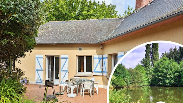 Ein Haus mit Terrasse, einem Tisch mit Stühlen und Blick auf einen Teich.