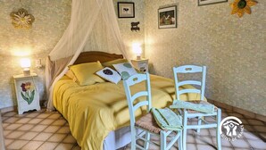 Ein Schlafzimmer mit einem Bett, zwei Nachttischen, einem Sessel und Wanddekorationen.
