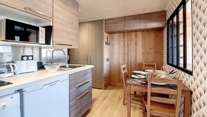 Une cuisine moderne avec un coin repas, des meubles en bois et une grande fenêtre.
