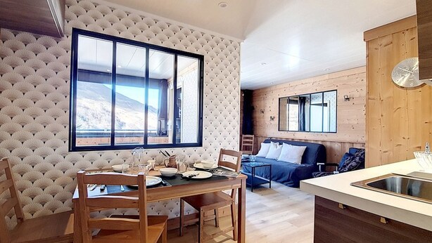 Un intérieur de chalet chaleureux avec un coin repas, un canapé et une cuisine.