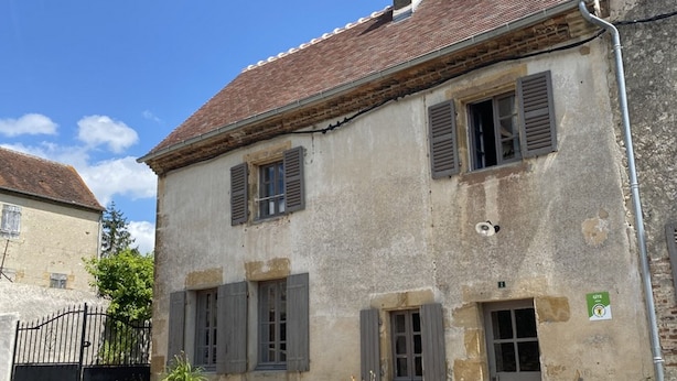A two-story building with a tiled roof and shuttered windows.