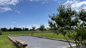 A rectangular paved area with a wooden border, surrounded by grass and trees. - Renovated cottage in Pierrefitte-sur-Loire with garden and parking (Pierrefitte-sur-Loire)