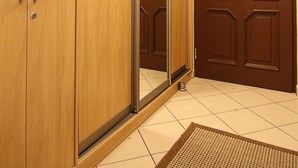 A room with a wooden wardrobe, a sliding door, and a tiled floor.